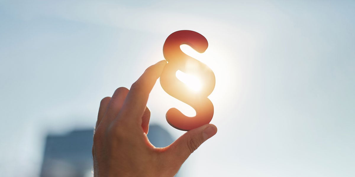 Hand hält Paragraph-Zeichen: Infos zur Kassensicherungsverordnung Hand hält Paragraph-Zeichen: Infos zur Kassensicherungsverordnung